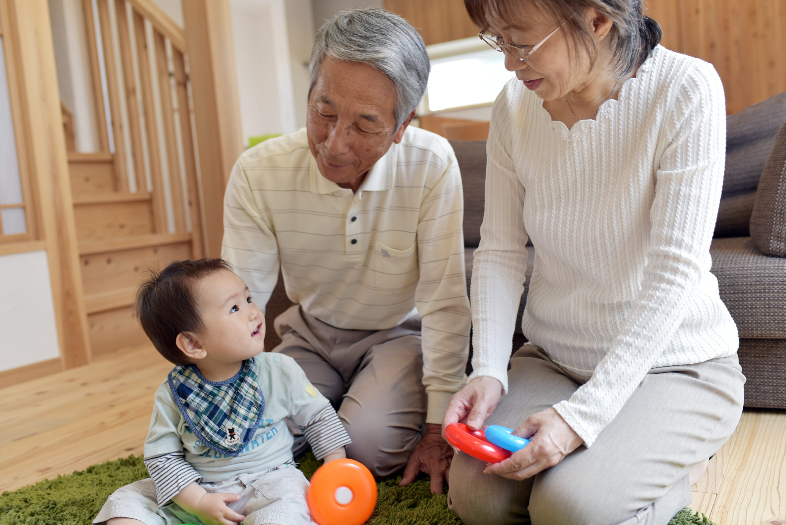 Two asian grandparents playing with toys with their young grandchild.